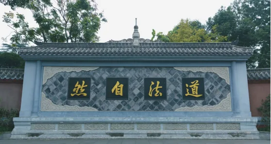 Stone screen wall with 'Dao Fa Zi Ran' calligraphy and Ming dynasty stone lions at temple entrance
