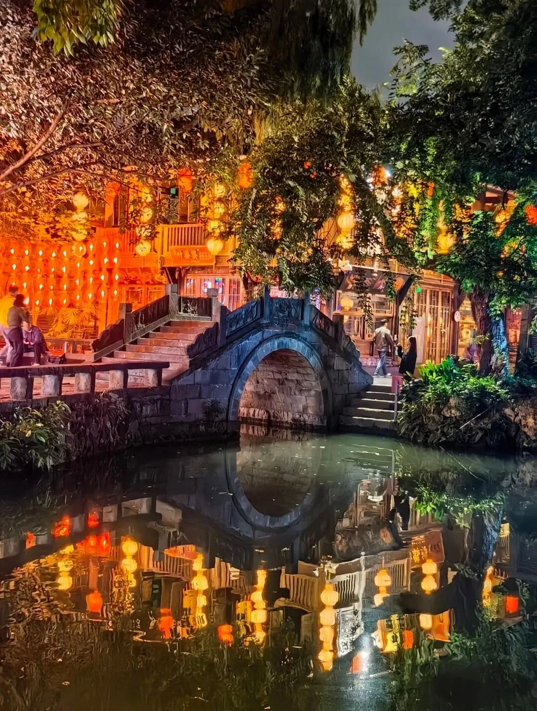 Jinli Ancient Street stone bridge over pond with lantern reflections at night
