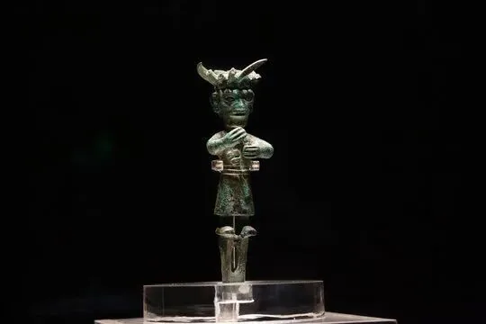 Small bronze standing figure with hollow fists, reminiscent of Sanxingdui statues