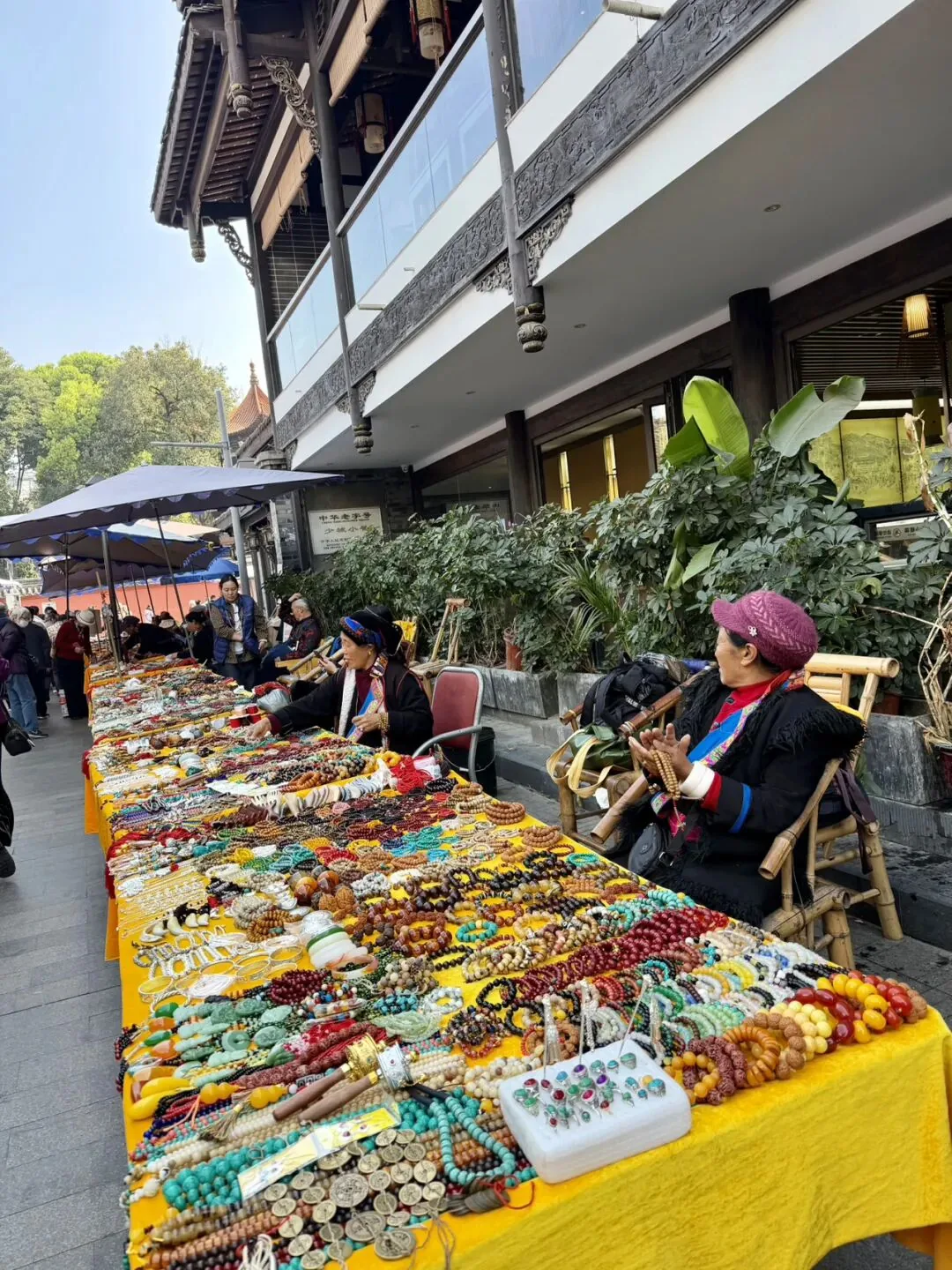 Street vendor selling colorful Tibetan bead necklaces and prayer wheels at Wenshu Fang