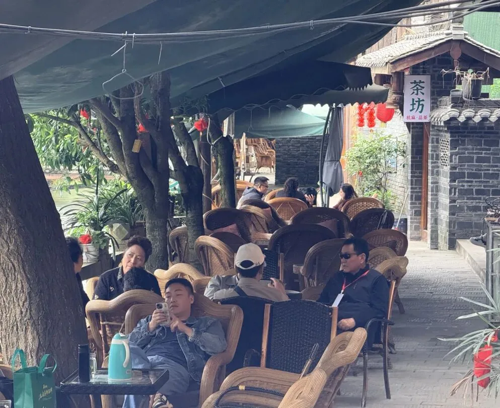 Locals playing cards and chatting at a riverside teahouse in Xinchang